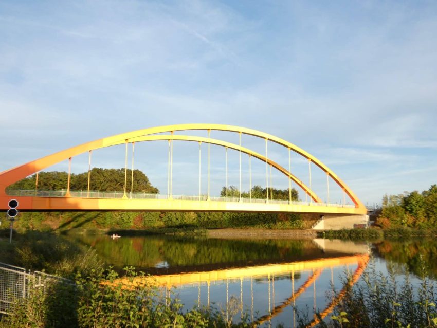 gelborange Bogenbrücke über Fluss